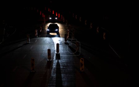 Téléchargez les photos : Voitures sur une route avec travaux routiers. Il travaille sur la route. Circulation nocturne. - en image libre de droit