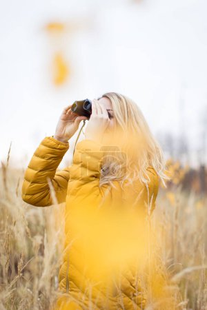 Photo for Young woman with binoculars outdoors on fall day. Enjoying the outdoors. - Royalty Free Image
