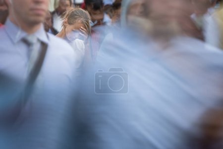 Photo for Crowd of people walking on city street - motion blurred image with unrecognizable faces - Young woman standing still, feeling down, depressed - Royalty Free Image