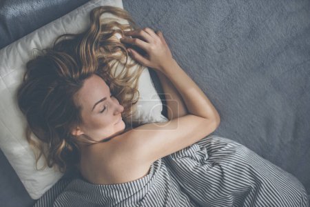 Foto de Mujer joven y bonita que duerme en su cama por la mañana un fin de semana, compensando la falta de sueño - Imagen libre de derechos