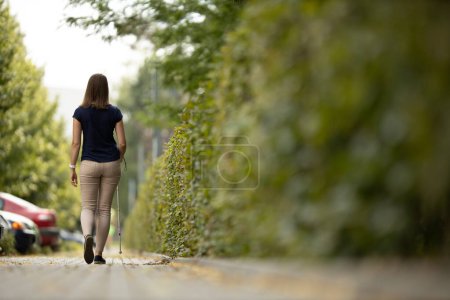 Foto de Mujer ciega caminando por las calles de la ciudad, usando su bastón blanco - Imagen libre de derechos