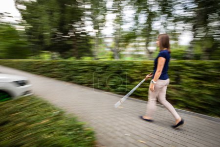 Foto de Mujer ciega caminando por las calles de la ciudad, usando su bastón blanco - Imagen libre de derechos