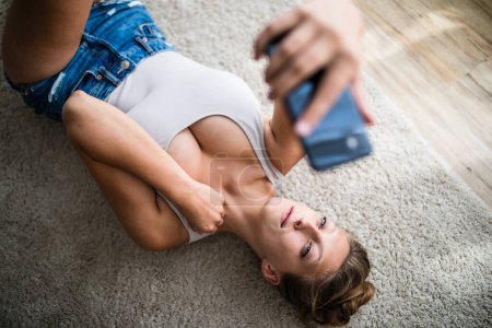 Téléchargez les photos : Attrayant jeune femme prenant selfies avec son smartphone - en image libre de droit