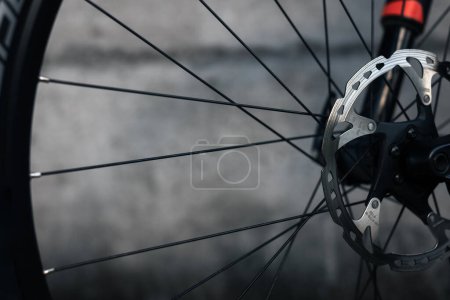 Photo for Hydraulic bicycle disk brakes, grey metal disc attached to bike wheel close up, effective popular mountain bicycle brakes. Hydraulic disk brakes on bicycle wheel, bicycle spokes gray background - Royalty Free Image