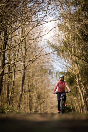 Téléchargez les photos : Jolie, jeune femme avec son vélo de montagne va faire un tour au-delà des limites de la ville, obtenir la dose quotidienne de cardio - en image libre de droit