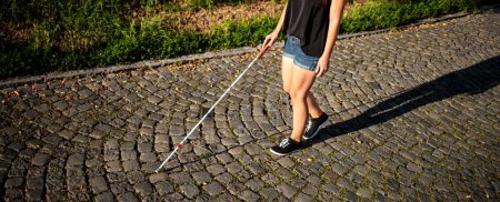 Photo for Blind woman walking on city streets, using her white cane to navigate the urban space better and to get to her destination safely - Royalty Free Image