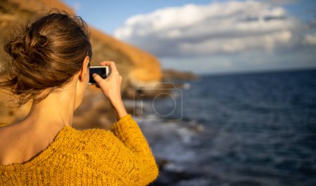 Téléchargez les photos : Jolie, jeune femme prenant des photos avec son smartphone pendant ses vacances - en image libre de droit