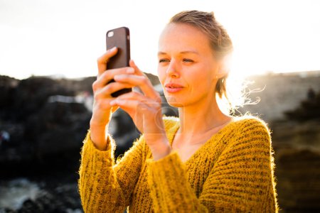 Téléchargez les photos : Jolie, jeune femme prenant des photos avec son smartphone pendant ses vacances - en image libre de droit
