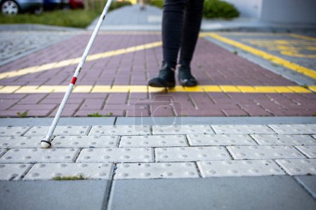 Foto de Mujer ciega caminando por las calles de la ciudad, usando su bastón blanco para navegar mejor por el espacio urbano y llegar a su destino con seguridad - Imagen libre de derechos