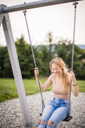 Photo for Spring romantic woman swinging on swing. Banner for website header. Carefree woman enjoy summer. Young woman is swinging on a swing in summer park garden. - Royalty Free Image