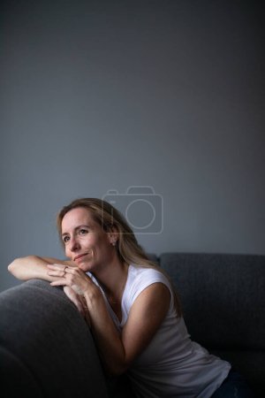 Foto de Mujer deprimida de mediana edad en casa sintiéndose triste, sola, ansiosa (imagen tonificada en color) - Imagen libre de derechos