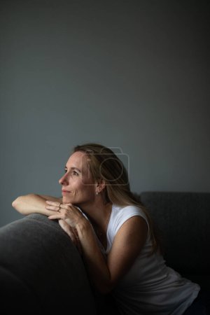Photo for Depressed mid-aged woman at home feeling sad, lonely, anxious (color toned image) - Royalty Free Image