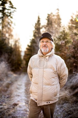 Foto de Feliz hombre mayor caminando afuera. Retrato del hombre mayor en un bosque en un día de invierno. - Imagen libre de derechos