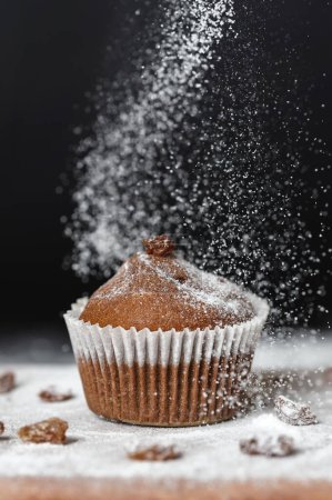 Photo for Fresh muffins sprinkled with powdered sugar over a wooden board - Royalty Free Image