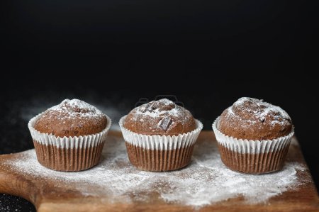 Photo for Fresh muffins on a wooden board in front of a dark background - Royalty Free Image