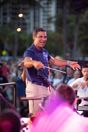 Téléchargez les photos : Le maire de Miami Francis X. Suarez dirige l'Orchestre symphonique de Miami au Peacock Park à Coconut Grove, FL, le 4 juillet 2022 - en image libre de droit