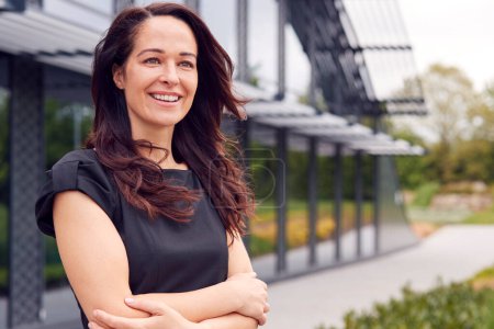 Portrait Of Smiling Mature Businesswoman CEO Chairperson Standing Outside Modern Office Building