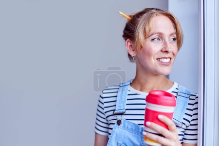 Mujer decoración habitación en casa tomando un descanso con bebida caliente en taza reutilizable