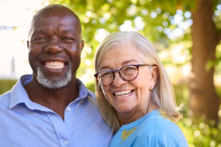 Porträt eines liebenden, multirassischen Senioren-Paares, das im Freien im Garten oder auf dem Land steht