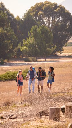 Group Of Friends With Backpacks Hiking In Countryside Together