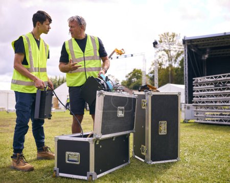 Produktionsteam packt Lichter aus Flugkoffer aus und baut Outdoor-Bühne für Musikfestival auf