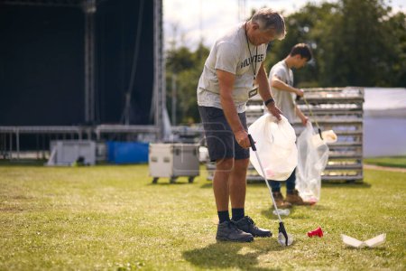 Freiwillige sammeln Müll nach Outdoor-Veranstaltung wie Konzert oder Musikfestival ein