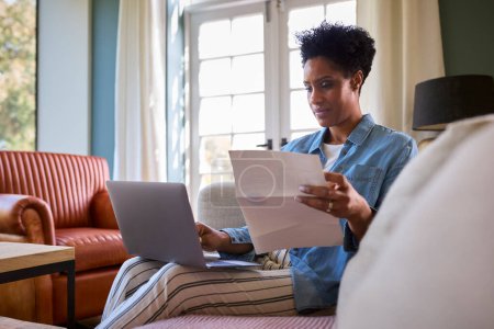 Worried Mature Woman At Home With Laptop Looking At Household Bills In Cost Of Living Crisis
