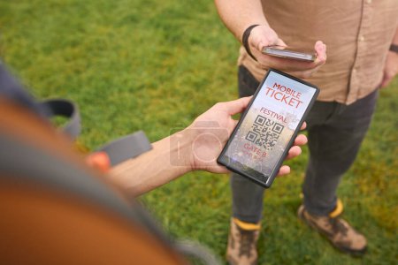 Close Up Of Person Showing E Ticket On Mobile Phone At Entrance To Outdoor Concert