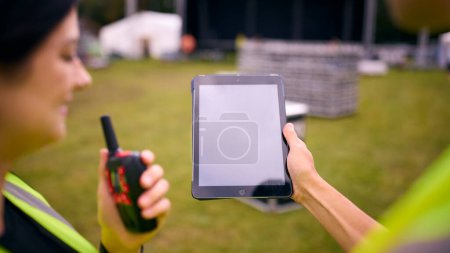 Nahaufnahme des Produktionsteams mit Blick auf das digitale Tablet beim Aufbau der Outdoor-Bühne für das Musikfestival