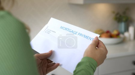 Nahaufnahme einer Frau, die einen Brief über die Erhöhung der Rückzahlung von Hypotheken während der Lebenshaltungskosten eröffnet