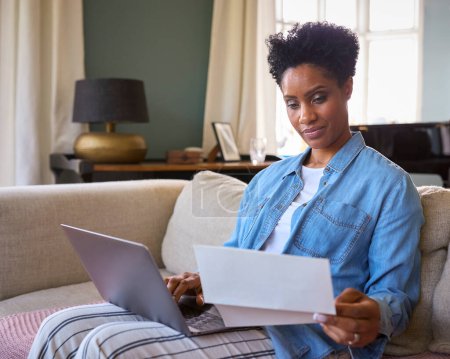 Worried Mature Woman At Home With Laptop Looking At Household Bills In Cost Of Living Crisis