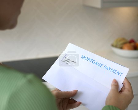 Nahaufnahme einer Frau, die einen Brief über die Erhöhung der Rückzahlung von Hypotheken während der Lebenshaltungskosten eröffnet