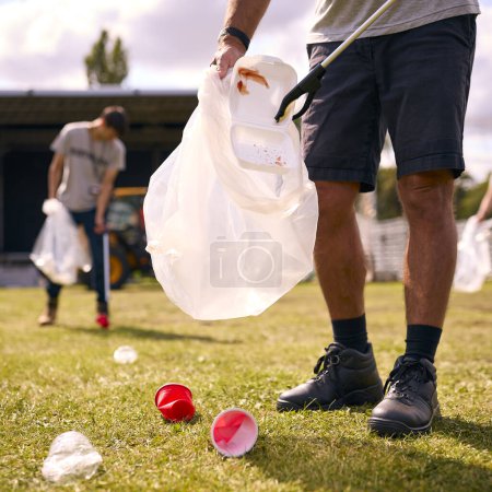 Close Up Of Volunteers Picking Up Litter After Outdoor Event Like Concert Or Music Festival