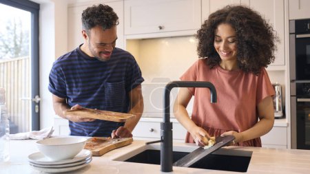 Paar zu Hause mit Mann mit Down-Syndrom und Frau räumt auf und spült Geschirr nach dem Essen