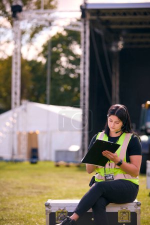 Travailleur de production féminine installant la scène extérieure pour le festival de musique ou le concert
