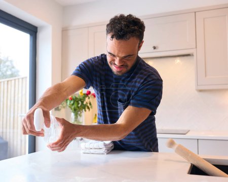 Mann mit Down-Syndrom putzt und räumt nach dem Essen in der Küche auf