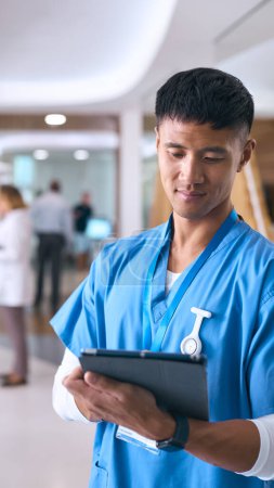 Männlich Arzt oder Krankenschwester tragen Peelings im Krankenhaus mit Kollegen im Hintergrund