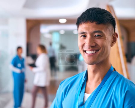 Retrato de un sonriente doctor o enfermera usando exfoliantes en el hospital con su colega en segundo plano