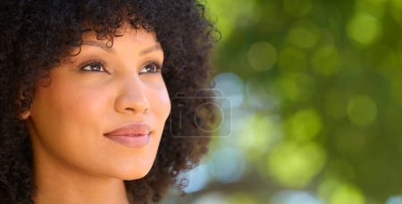 Head And Shoulders Portrait Of Smiling Woman Outside Relaxing In Countryside Looking At Camera