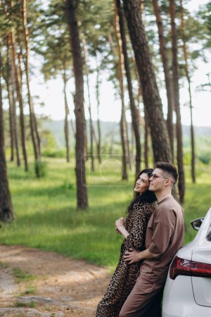 Téléchargez les photos : Adorable jeune couple étreignant près de la voiture - en image libre de droit