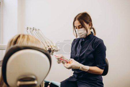 Foto de Dentista y paciente eligiendo el tratamiento en una consulta con equipo médico en el fondo - Imagen libre de derechos