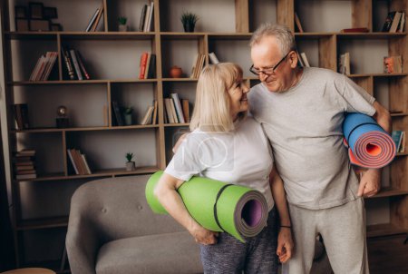 Téléchargez les photos : Couple âgé fait de la formation de remise en forme à la maison.Debout avec tapis de yoga de remise en forme. Concept de mode de vie sain
. - en image libre de droit