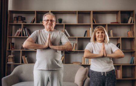 Foto de La pareja de ancianos está haciendo entrenamiento físico en casa. Haciendo yoga juntos. concepto de estilo de vida saludable
. - Imagen libre de derechos