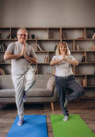 Foto de La pareja de ancianos está haciendo entrenamiento físico en casa. Haciendo yoga juntos. concepto de estilo de vida saludable
. - Imagen libre de derechos