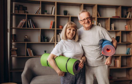 Téléchargez les photos : Heureux couple de personnes âgées en bonne santé des années 60 bénéficiant d'entraînement sportif de remise en forme ensemble dans l'appartement - en image libre de droit