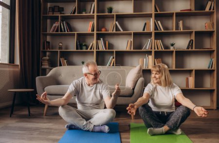 Foto de Feliz sana pareja de mayores de 60 años disfrutando de entrenamiento deportivo de fitness juntos en el apartamento - Imagen libre de derechos