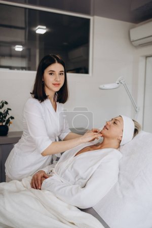Photo for The doctor cosmetologist makes Lip augmentation procedure of a beautiful woman in a beauty salon. Prp therapy, anti wrinkle and aging skin. Cosmetology skin care. - Royalty Free Image