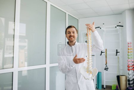 Photo for A vertebrologist holds a model of the spine in his hand - Royalty Free Image