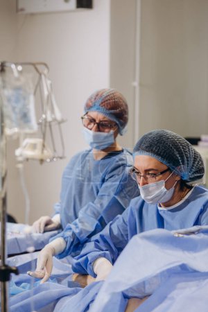 Foto de El equipo de cirujanos uniformados realiza una operación de corrección de venas varicosas en un paciente de la clínica de cirugía. flebología - Imagen libre de derechos