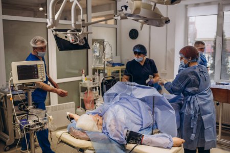 Foto de El equipo de cirujanos uniformados realiza una operación de corrección de venas varicosas en un paciente en la clínica de cirugía
. - Imagen libre de derechos